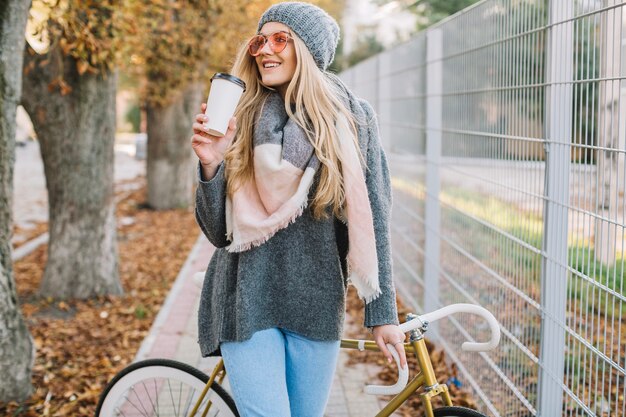 Femme joyeuse avec tasse et vélo