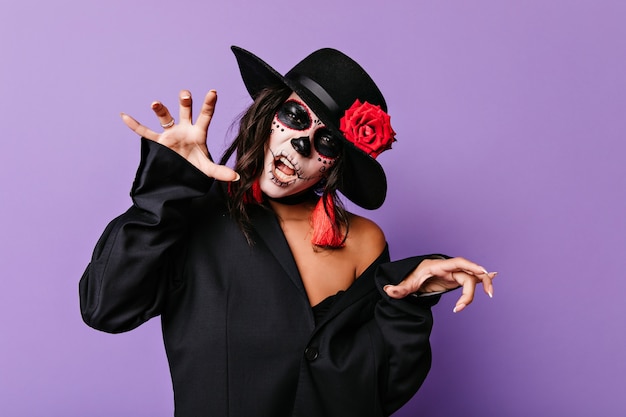 Photo gratuite femme joyeuse en tenue muertos s'amusant à la fête. incroyable modèle féminin avec la peinture de visage de zombie posant à halloween.