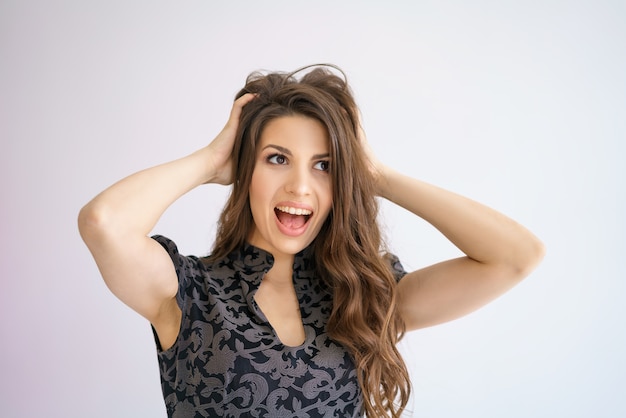 Photo gratuite une femme joyeuse tient sa tête avec ses mains en surprise sur fond blanc