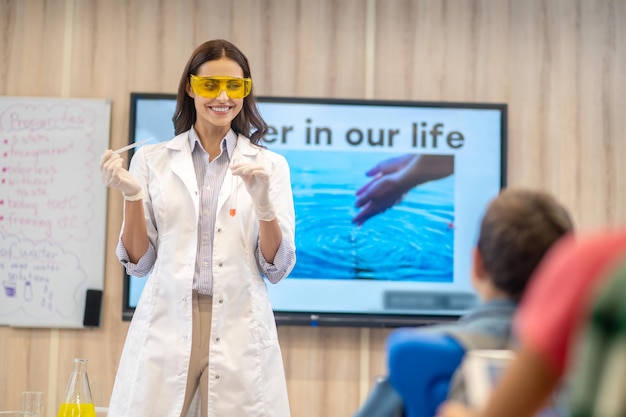 Photo gratuite femme joyeuse avec tube à essai regardant les enfants