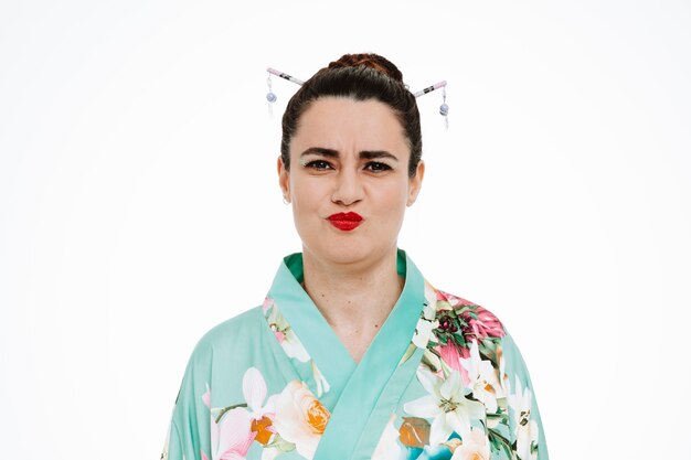 Femme en kimono japonais traditionnel étant ennuyé de souffler des joues sur blanc