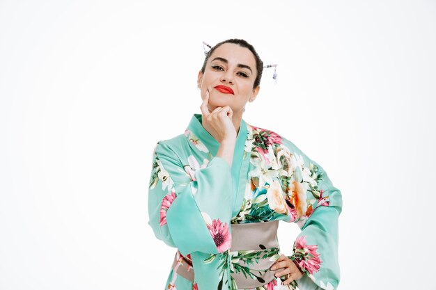 Femme en kimono japonais traditionnel avec une expression pensive tenant la main sur son menton pensant sur le blanc