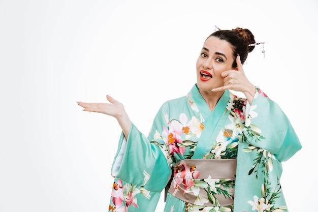 Femme en kimono japonais traditionnel heureux et positif montrant appelez-moi geste présentant quelque chose avec le bras de sa main sur blanc