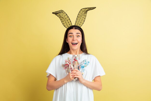 Femme de lapin de Pâques avec des émotions vives sur mur jaune