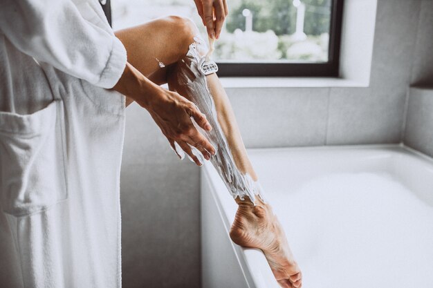 Femme laver les jambes à la maison dans la salle de bain