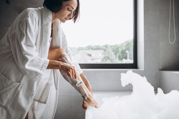 Femme laver les jambes à la maison dans la salle de bain