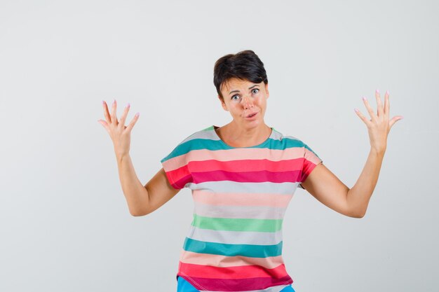 Femme levant les bras en t-shirt rayé et à la confusion. vue de face.