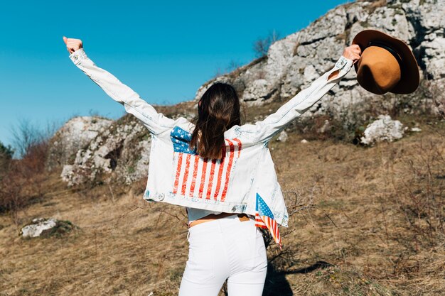 Femme levant les mains avec un chapeau dans la nature