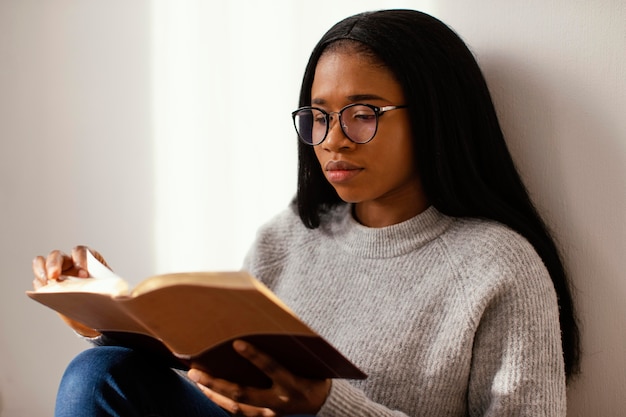 Femme lisant la Bible à l'intérieur