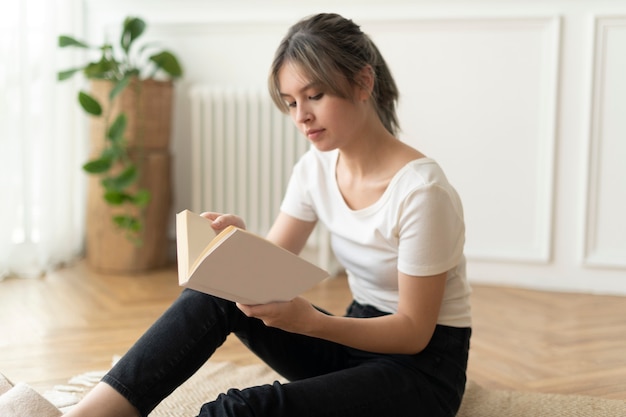 Femme lisant un livre assis sur un sol