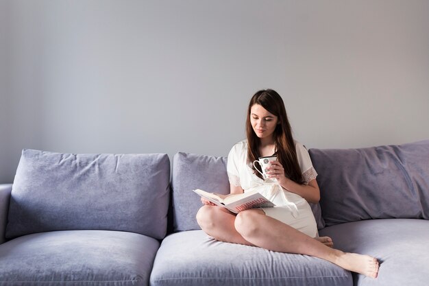 Femme lisant un livre sur le canapé