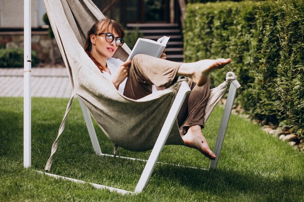 Femme lisant un livre dans le jardin près de la maison