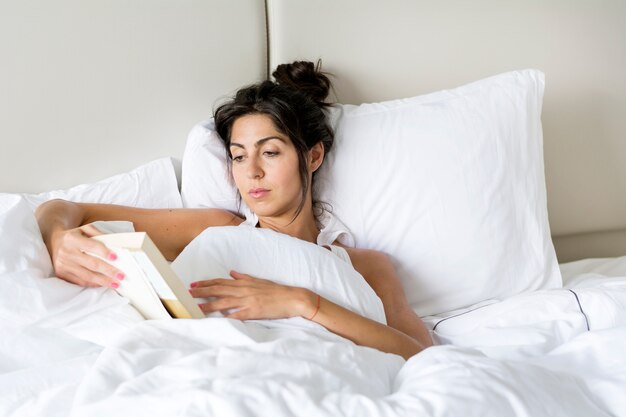 Femme lisant un livre dans le lit