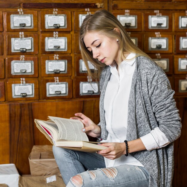 Femme lisant près des paquets et du catalogue