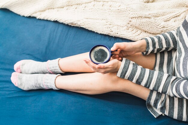 Femme sur le lit avec le café dans les mains