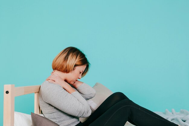 Femme sur le lit avec le cou dans la douleur