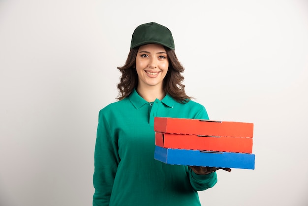 Femme de livraison avec des boîtes à pizza posant sur blanc.