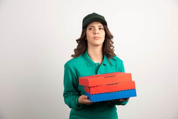 Femme de livraison avec des boîtes à pizza posant sur blanc.