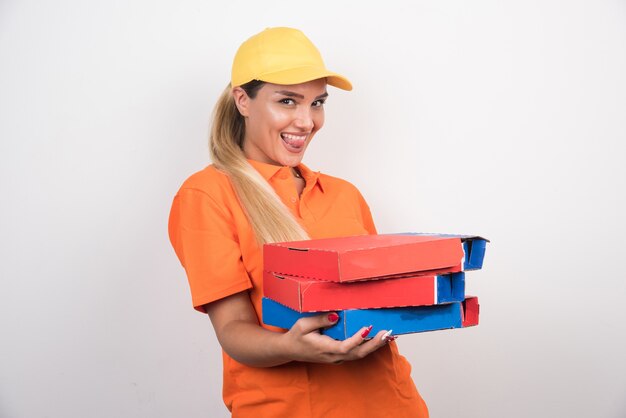 Femme de livraison avec chapeau jaune tenant des boîtes à pizza sur fond blanc.