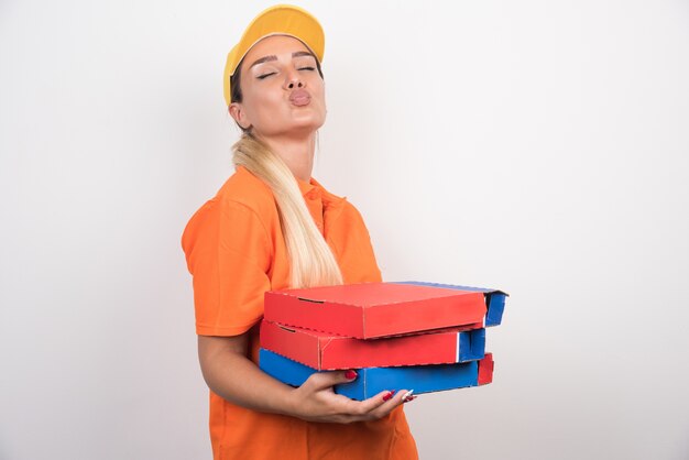 Femme de livraison avec chapeau jaune tenant des boîtes à pizza.