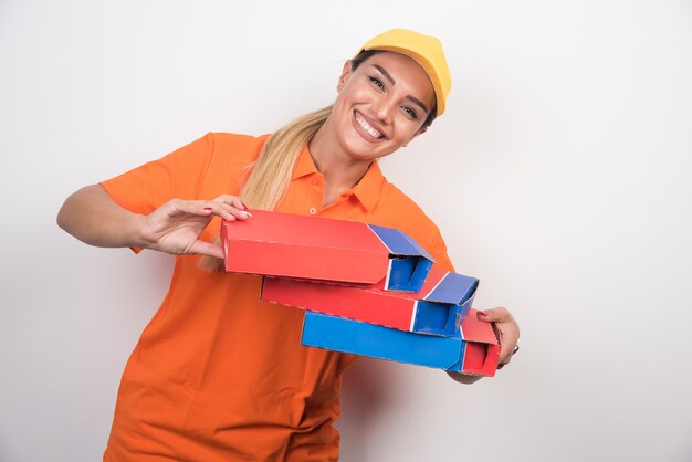 Femme de livraison avec chapeau jaune tenant des boîtes à pizza.