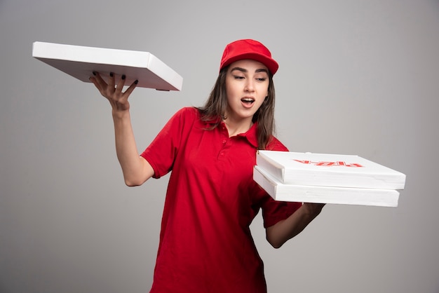 Photo gratuite femme de livraison essayant de garder trois pizzas sur sa main.