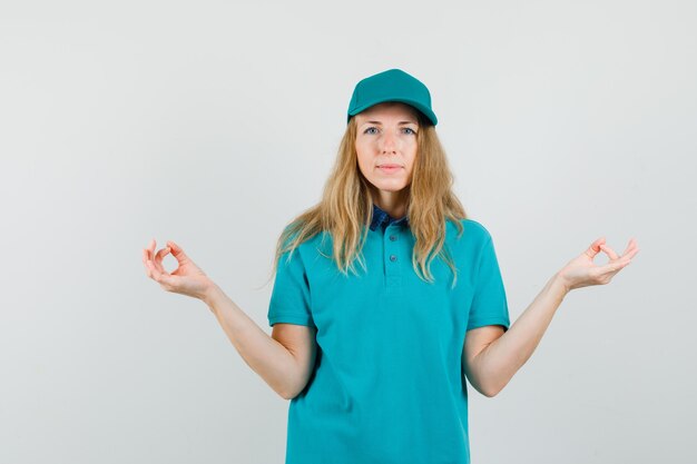 Femme de livraison faisant la méditation en t-shirt, casquette et à la paix