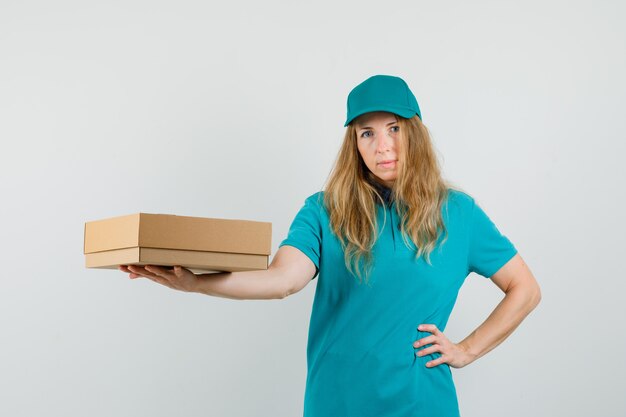 Femme de livraison montrant une boîte en carton en t-shirt, casquette