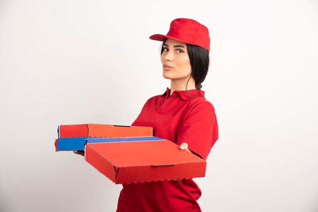 Femme de livraison de pizza jeune tenant des boîtes à pizza.