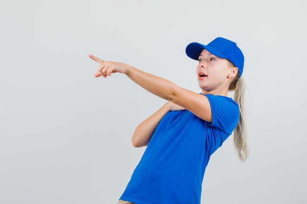 Femme de livraison pointant vers l'extérieur en t-shirt bleu et casquette et à la surprise