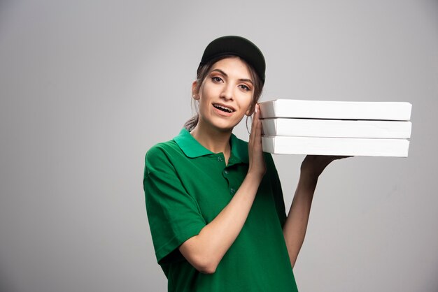 Femme de livraison posant avec des boîtes à pizza.