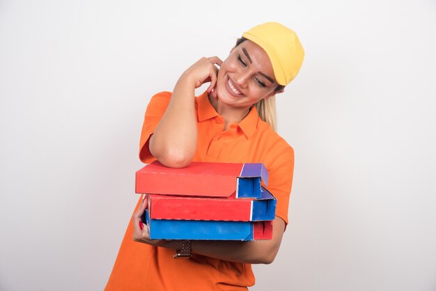 Femme de livraison souriante tenant des boîtes à pizza.