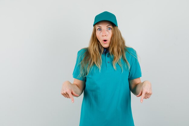 Femme de livraison en t-shirt, casquette pointant vers le bas et à la surprise