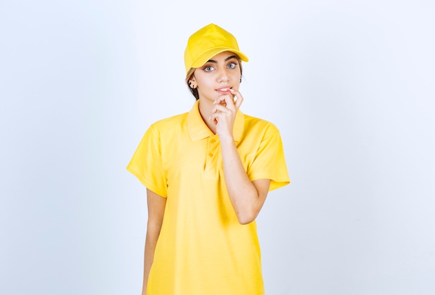 Femme de livraison en uniforme jaune debout et regardant la caméra.