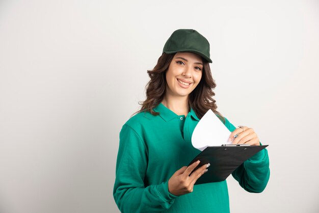 Femme de livraison en uniforme vert souriant à la caméra.