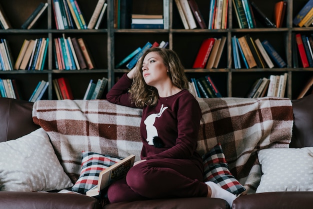 Femme avec un livre sur le canapé