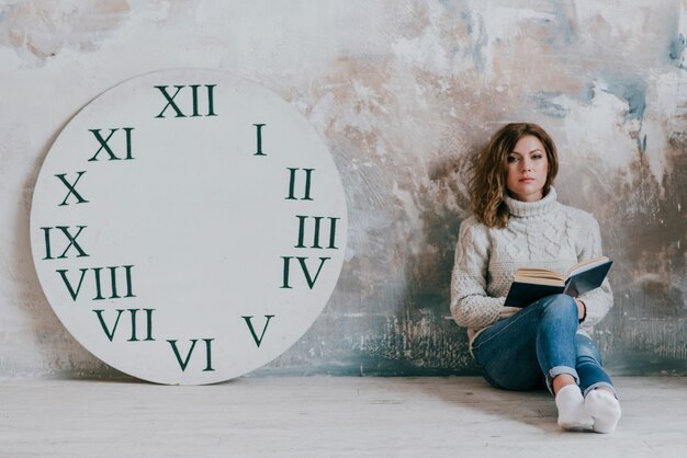 Femme avec livre près du disque de l&#39;horloge