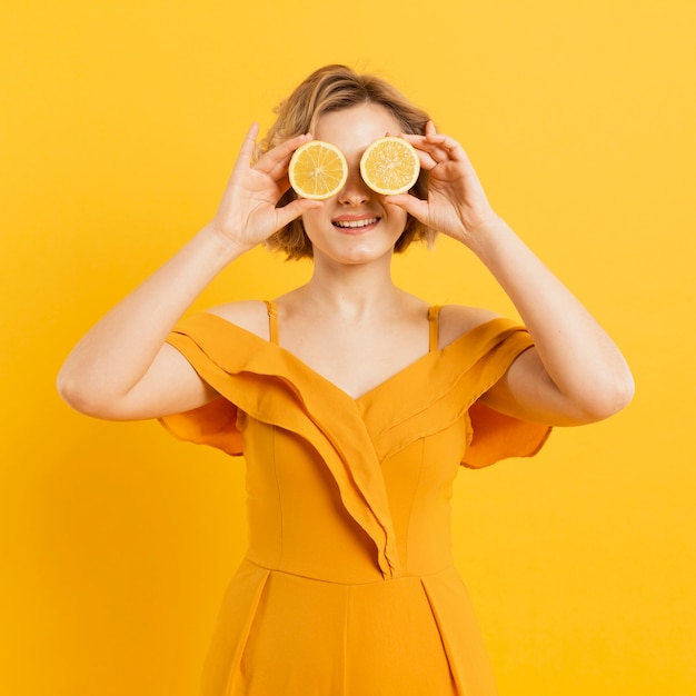 Femme ludique couvrant les yeux avec des tranches de citron