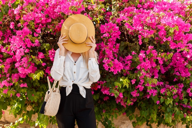 Photo gratuite femme ludique se cachant derrière le chapeau de paille