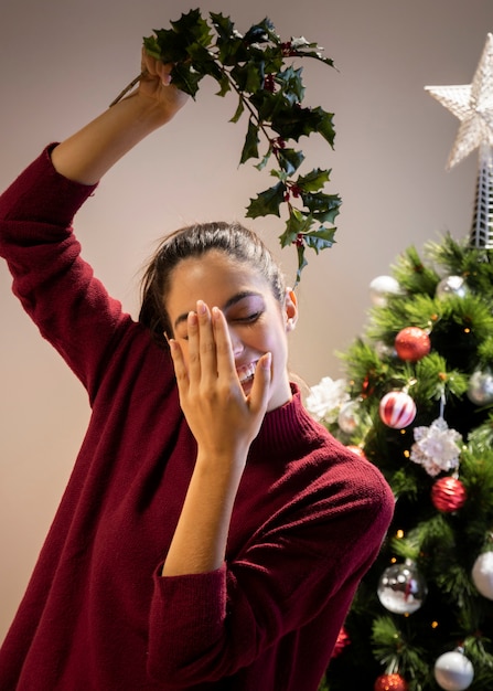 Femme ludique tenant le gui au-dessus de la tête