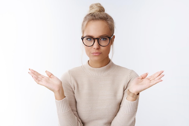 femme à lunettes avec coupe de cheveux chignon écarter les mains inconscientes et indifférentes se sentant insouciantes de ce que les gens chose posant sûr de soi