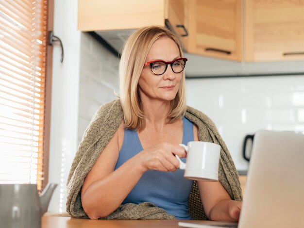 Femme avec des lunettes et un ordinateur portable pendant la quarantaine à la maison