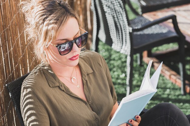 Femme à lunettes de soleil en appréciant le livre