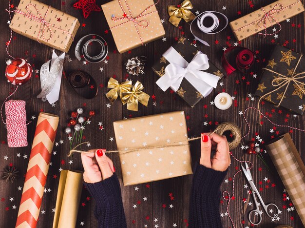 Femme main attachant l&#39;arc avec de la ficelle pour l&#39;emballage boîte de cadeau de Noël