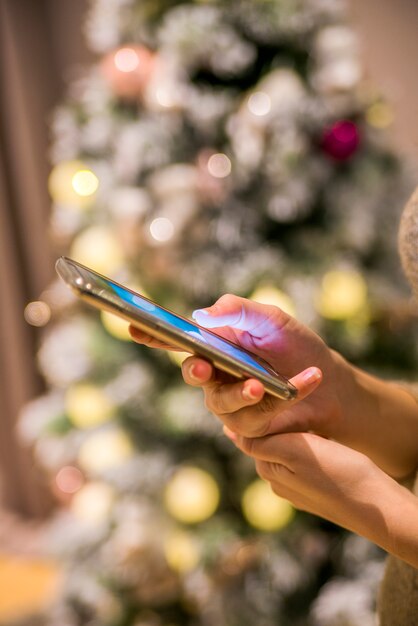 Femme, main, smartphone, noël, arbre, fond, closeup, femme, texting, smartphone, noël, arbre