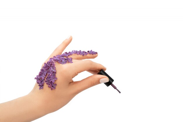 Femme main tenant une bouteille de vernis à ongles violet. Concept de printemps.