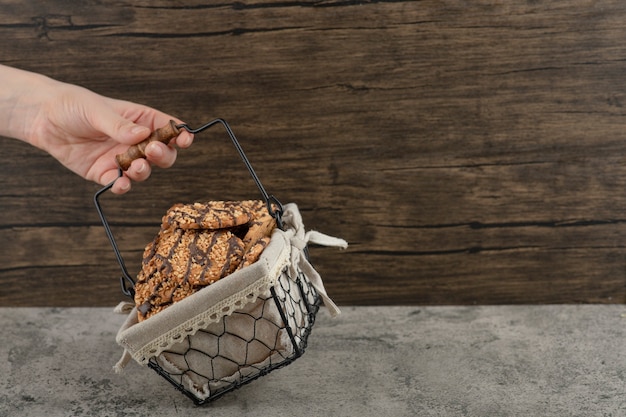 Femme main tenant le panier de biscuits frais sur une surface en marbre.