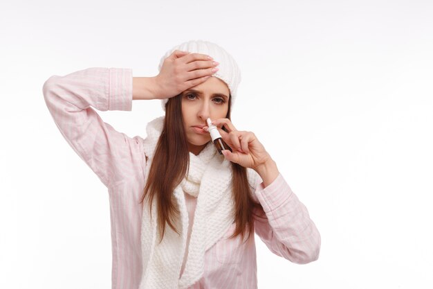 Femme avec une main sur la tête et un spray nasal