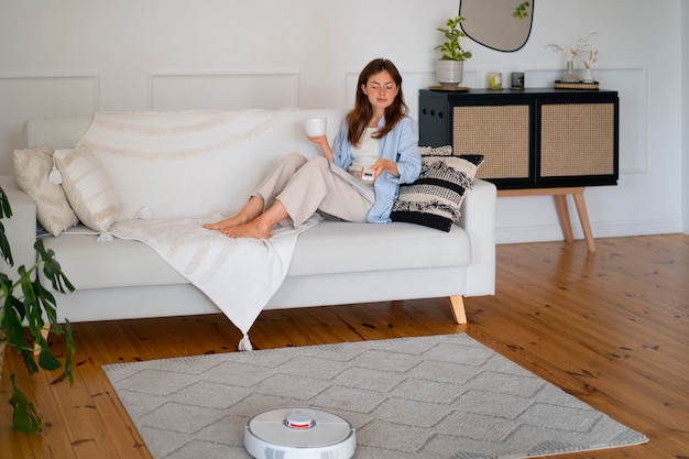 Photo gratuite femme à la maison avec un aspirateur robot sans fil