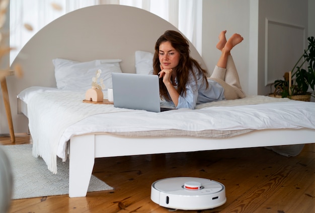 Photo gratuite femme à la maison avec un aspirateur robot sans fil